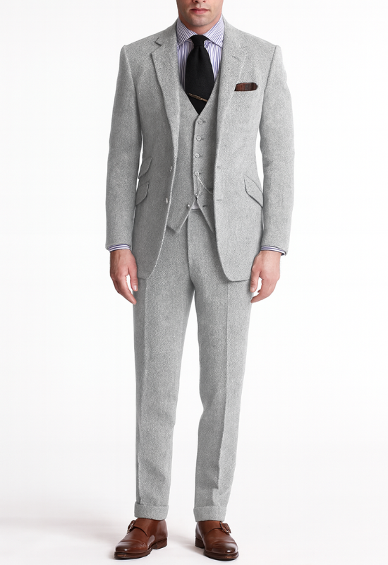 "Completo uomo elegante tre pezzi in tweed marrone tabacco, giacca monopetto, gilet abbottonato e pantaloni affusolati."