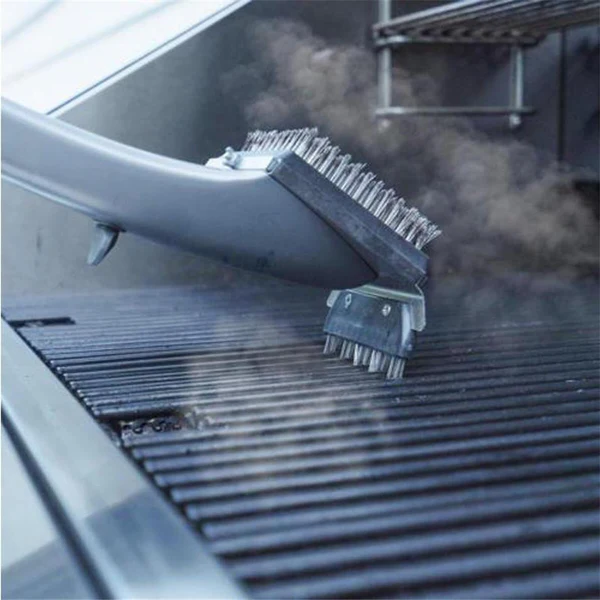 Close-up of a BBQ Steam Cleaning Brush effectively removing grime from a hot grill rack.