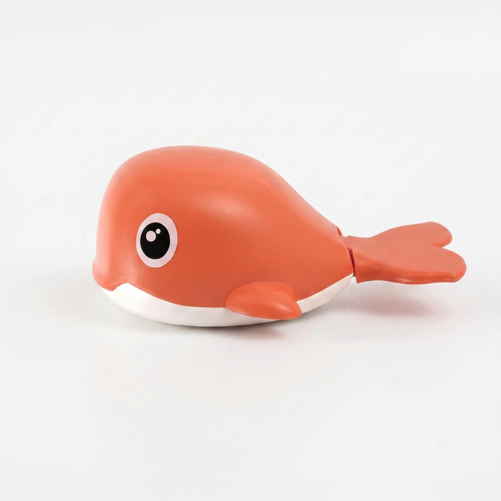 Toddler playing with a battery-free wind-up floating whale bath toy in the water, safe pool fun.
