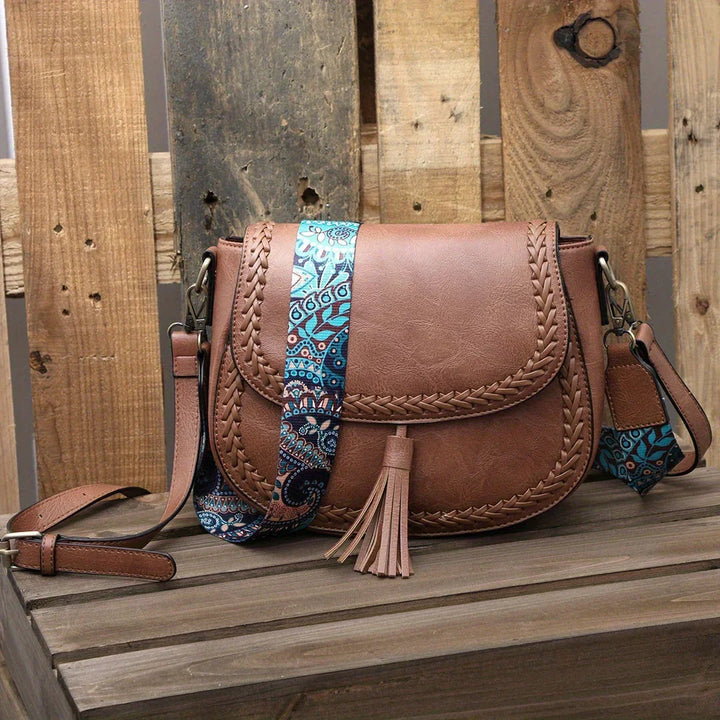 Stylish black women's saddle bag featuring a sophisticated tassel. Perfect everyday shoulder bag.