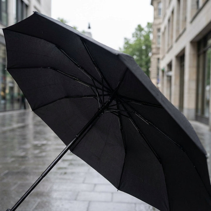 Compact black foldable umbrella with clip-on handle, perfect for portable travel and easy carry.