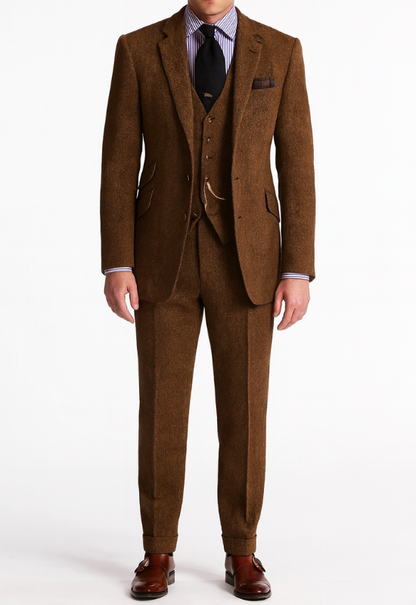 "Completo uomo elegante tre pezzi in tweed marrone tabacco, giacca monopetto, gilet abbottonato e pantaloni affusolati."