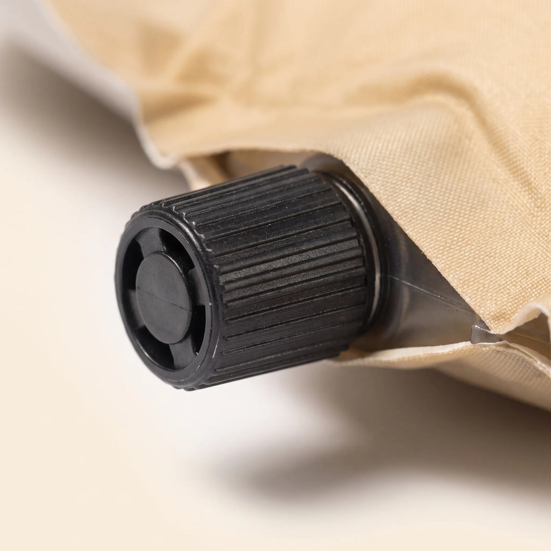 Cream self-inflating sleeping pad with pillow, essential portable outdoor gear for camping & hiking comfort.