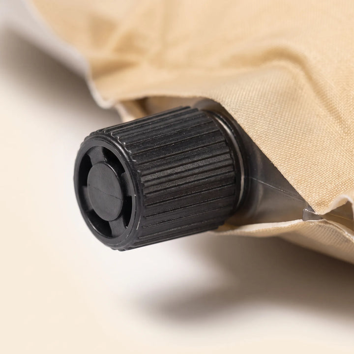 Cream self-inflating sleeping pad with pillow, essential portable outdoor gear for camping & hiking comfort.
