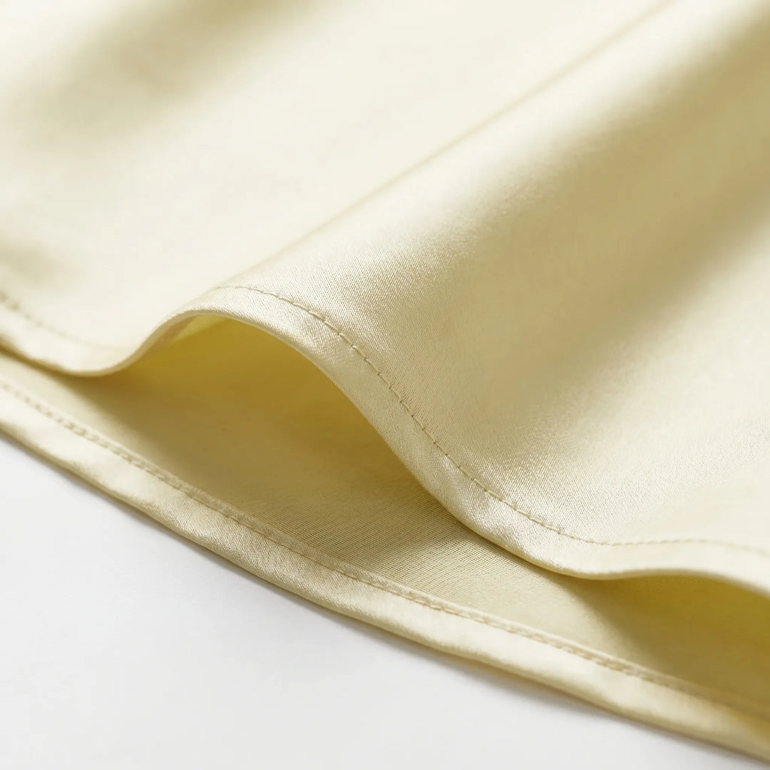 Sleeveless light yellow elegant slip dress for women, showcasing an open back and delicate scarf detail. Special occasion wear.