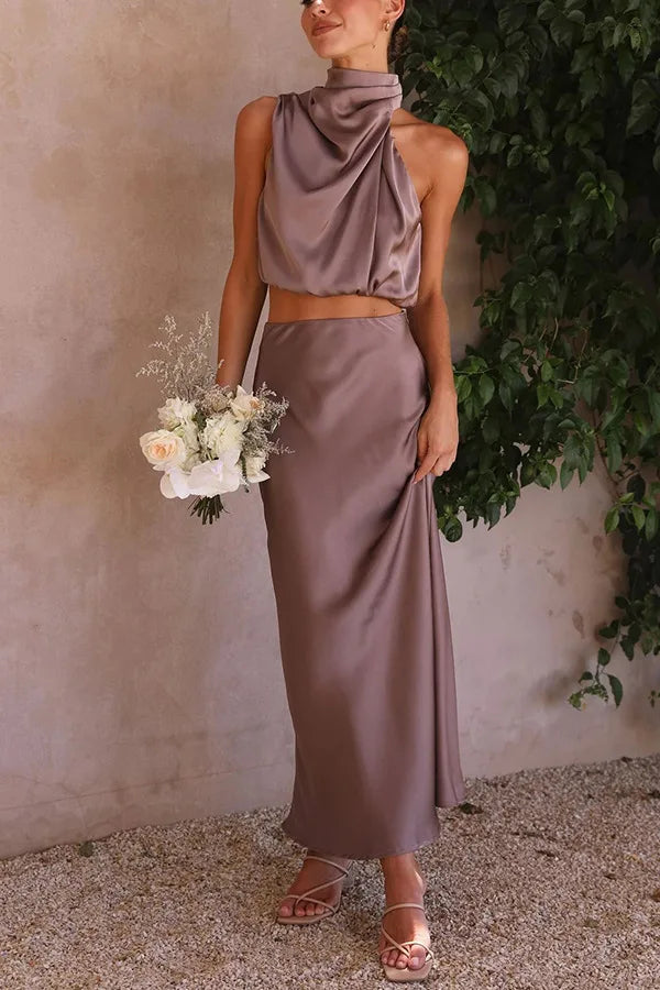 Sophisticated women's formal wear: a two-piece set featuring a draped halter top and a long, flowing maxi skirt.