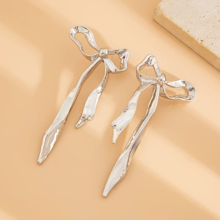 Elegant ribbon bow earrings. Gold-tone women's fashion accessory with a dainty, classic design. Versatile everyday jewelry.