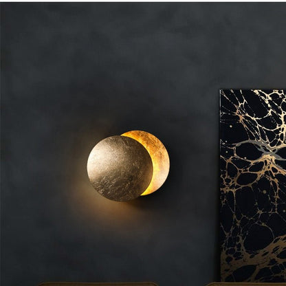 "Lampada da parete design eclisse, luce soffusa calda, metallo resistente, per atmosfera accogliente in soggiorno o camera."