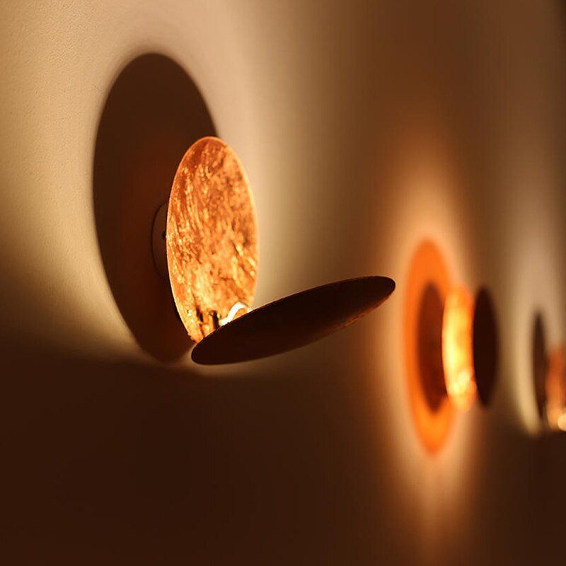 "Lampada da parete design eclisse, luce soffusa calda, metallo resistente, per atmosfera accogliente in soggiorno o camera."