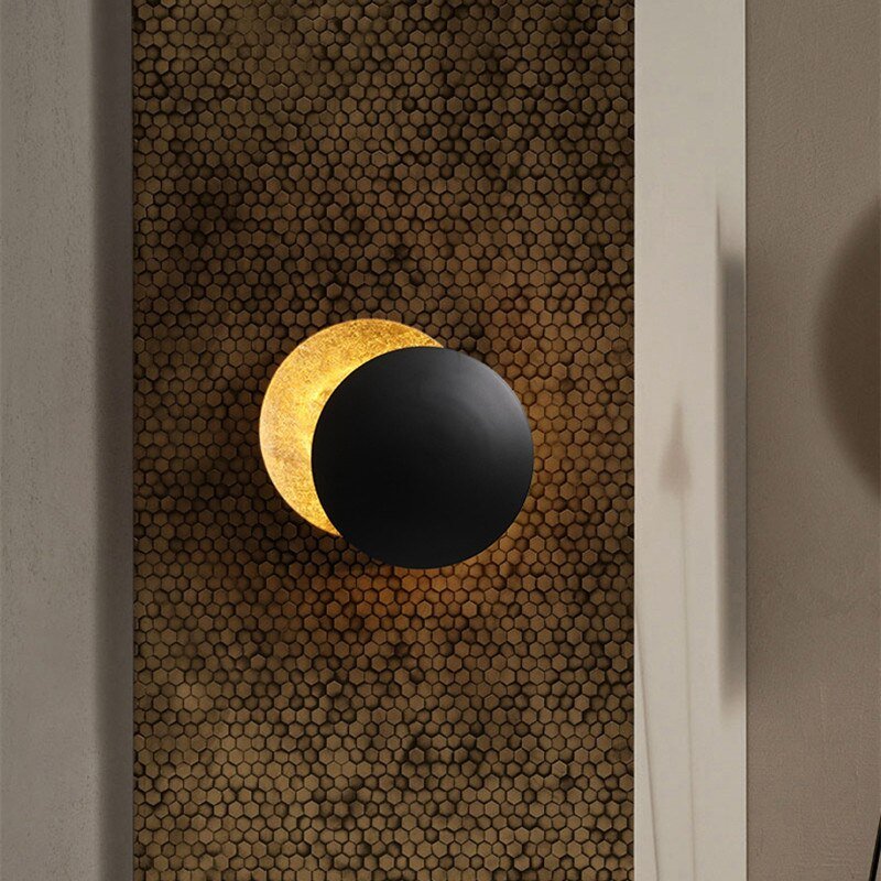 "Lampada da parete design eclisse, luce soffusa calda, metallo resistente, per atmosfera accogliente in soggiorno o camera."