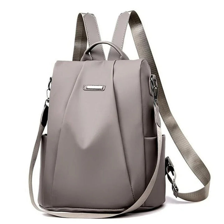 Woman wearing a lightweight, multi-way nylon backpack. Water-resistant, ideal for daily commute or travel.
