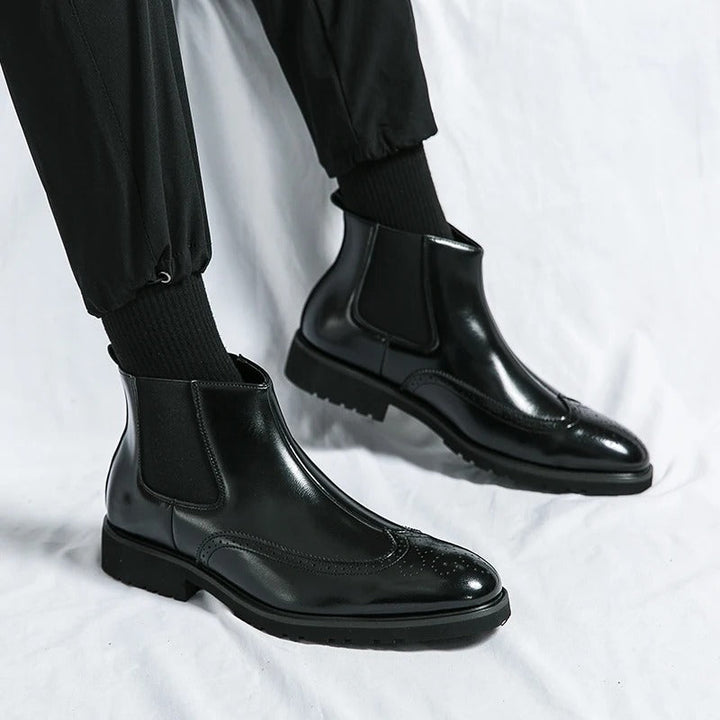 Men's black Chelsea boots with brogue detailing, combining comfort and sophisticated style.