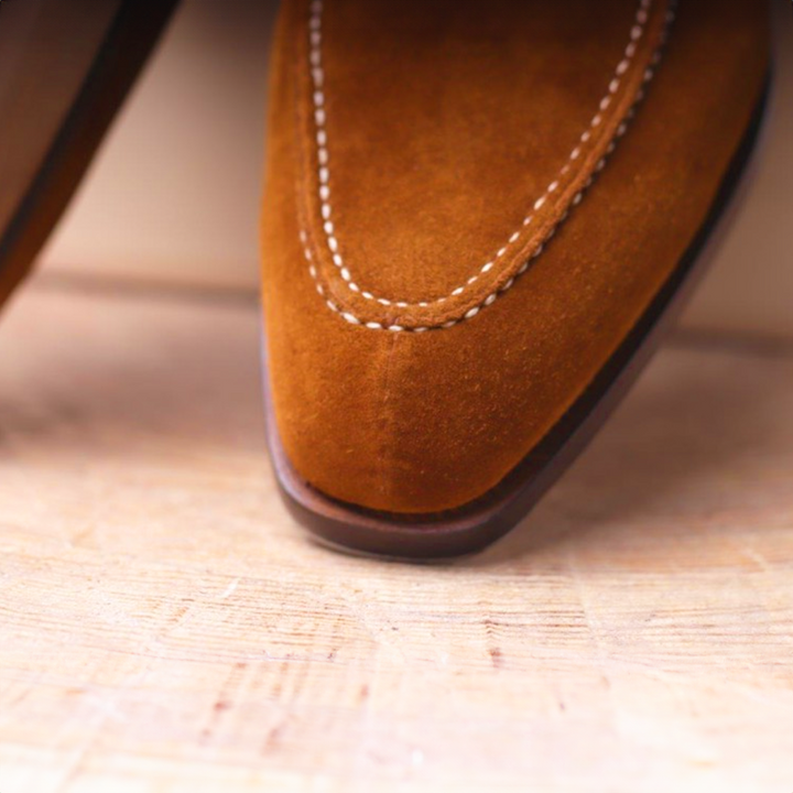 Man wearing stylish brown oxford dress shoes with a suit, perfect for formal or business casual attire.