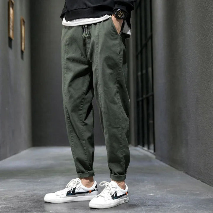 Man sitting in navy tapered joggers, showcasing flexible comfort for athleisure, loungewear & casual activities.