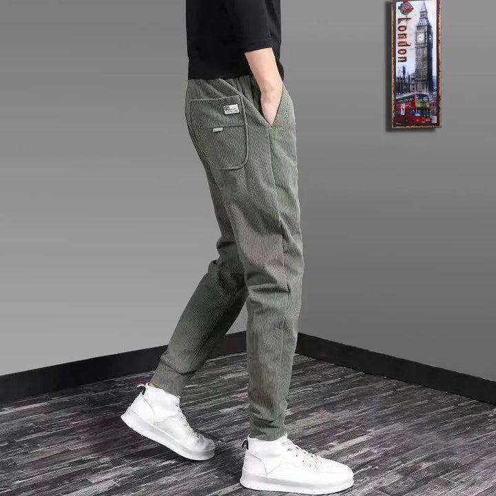 Man lounging comfortably in Men's Kaizen Jogger Pants. Relaxed fit, soft fabric ideal for casual wear at home.