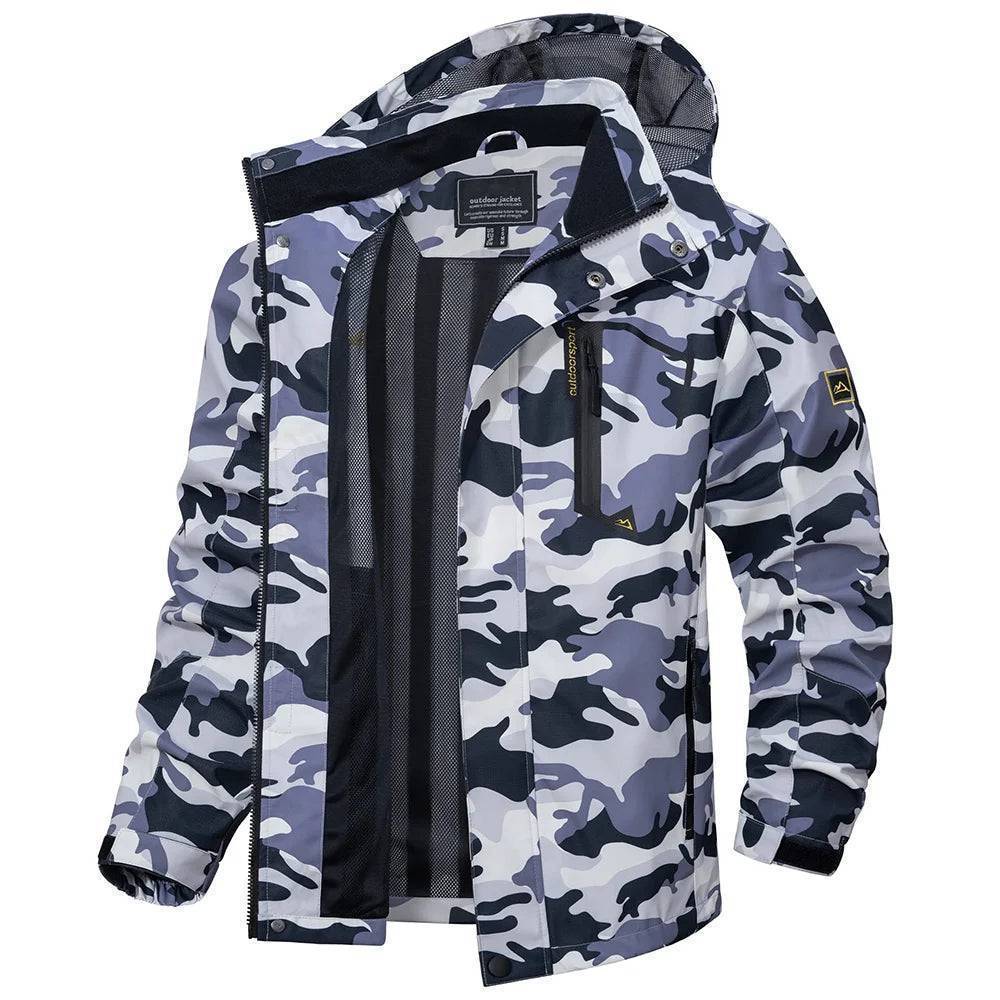 Man in a black lightweight waterproof rain jacket with detachable hood, standing by a lake.