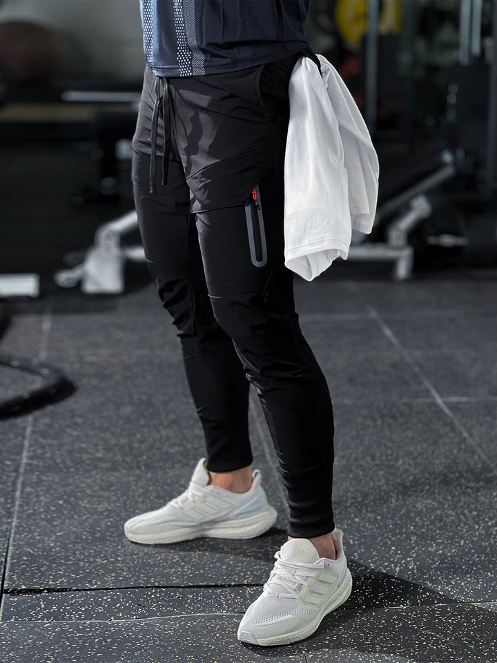 Black men's cargo joggers, performance fabric, tapered fit, utility pockets for versatile wear.