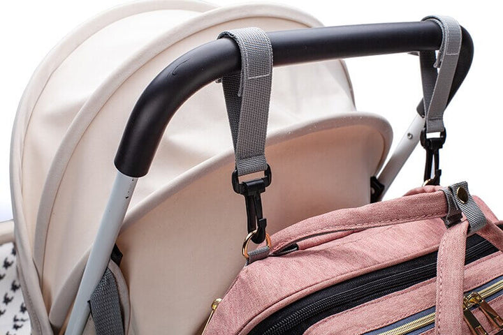 Unfolded portable baby bed with soft mattress, built into a travel diaper bag.