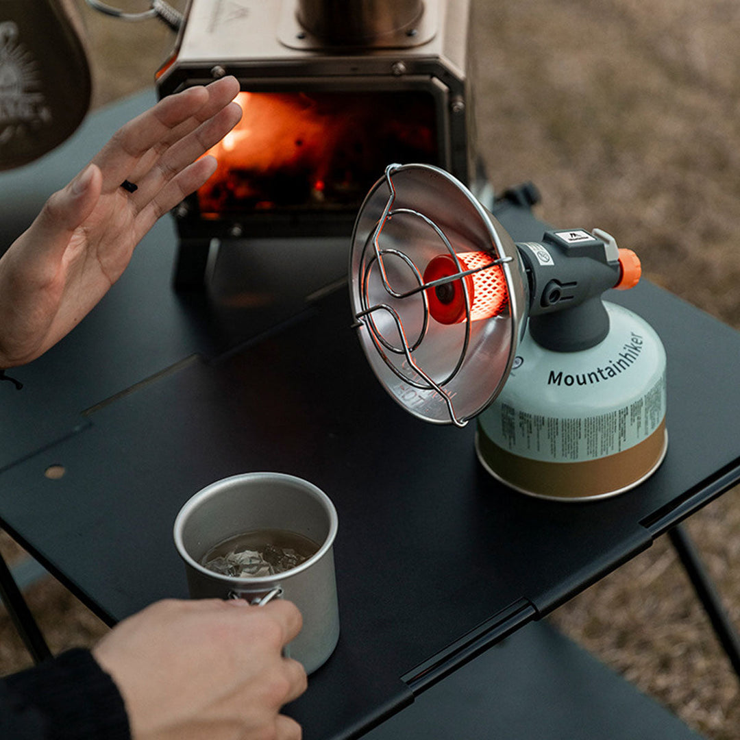 Side view of a portable butane heater, showcasing its compact size and suitability as winter camping gear.