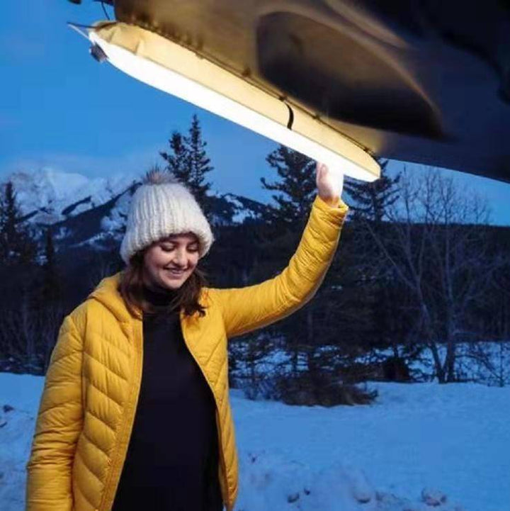 Versatile magnetic LED lantern, attached to a car hood, demonstrating strong magnetic hold for outdoor tasks.