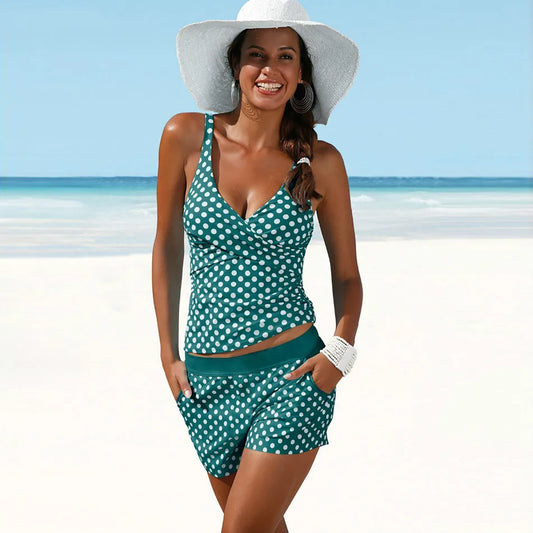 "Tankini donna nero e verde a pois, top incrociato con spalline, pantaloncini sportivi a vita alta, look estivo elegante."