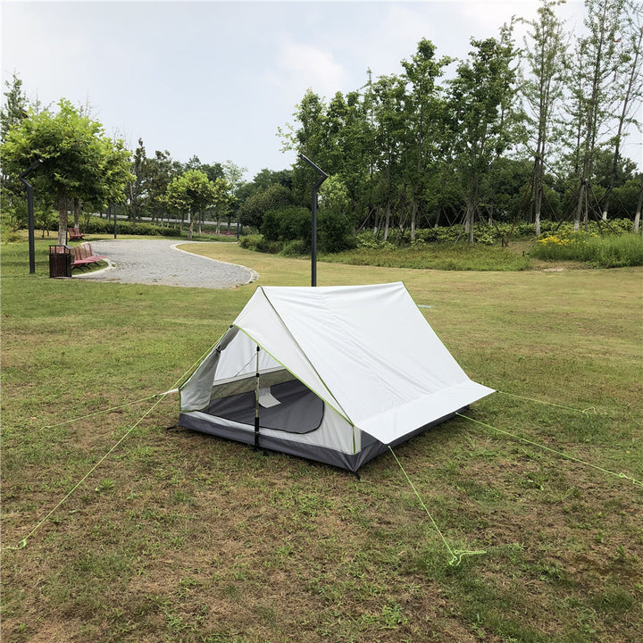 Backpacker setting up an ultralight A-frame tent with trekking poles.