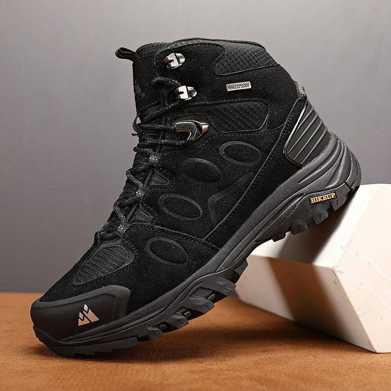 Pair of unisex grey trekking sneakers with orange laces, durable outdoor hiking shoes on a rocky trail