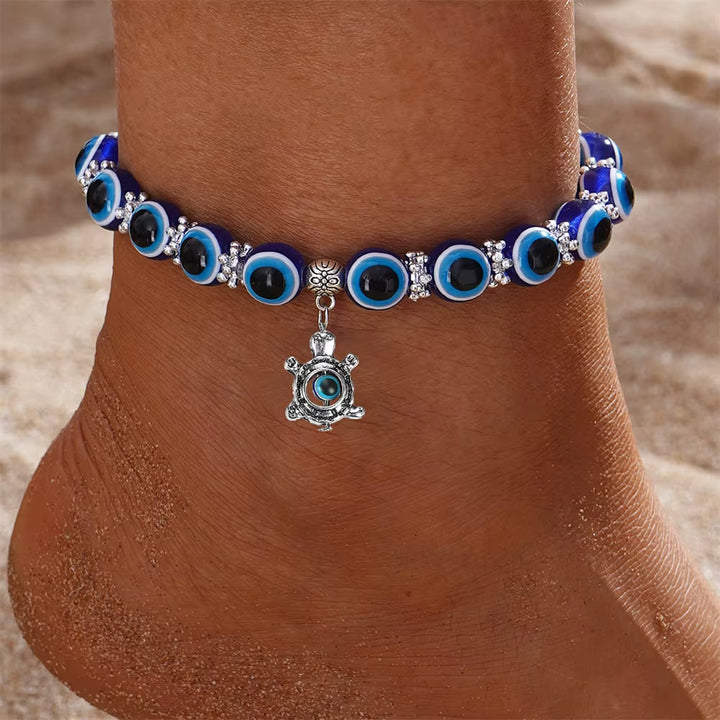 Close-up of a blue Evil Eye charm on a unisex protection anklet. Spiritual stretch fit symbolic jewelry for good luck.