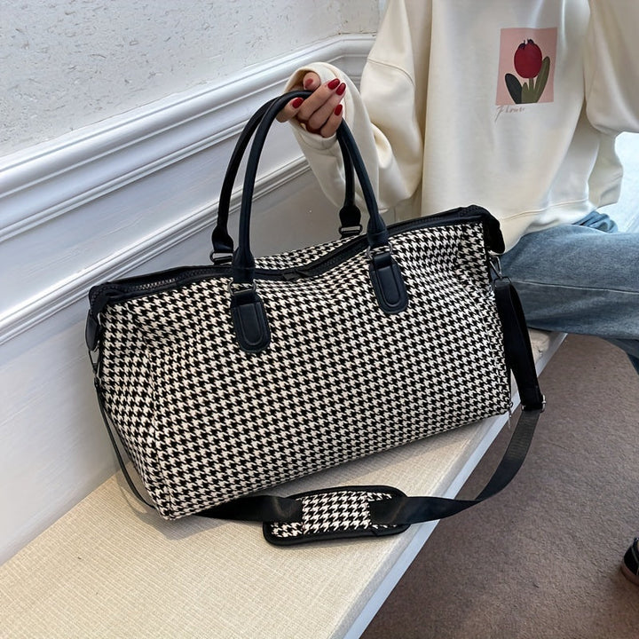 Detail of durable zippers on a unisex houndstooth weekender bag. Vegan leather travel duffle carry-on.