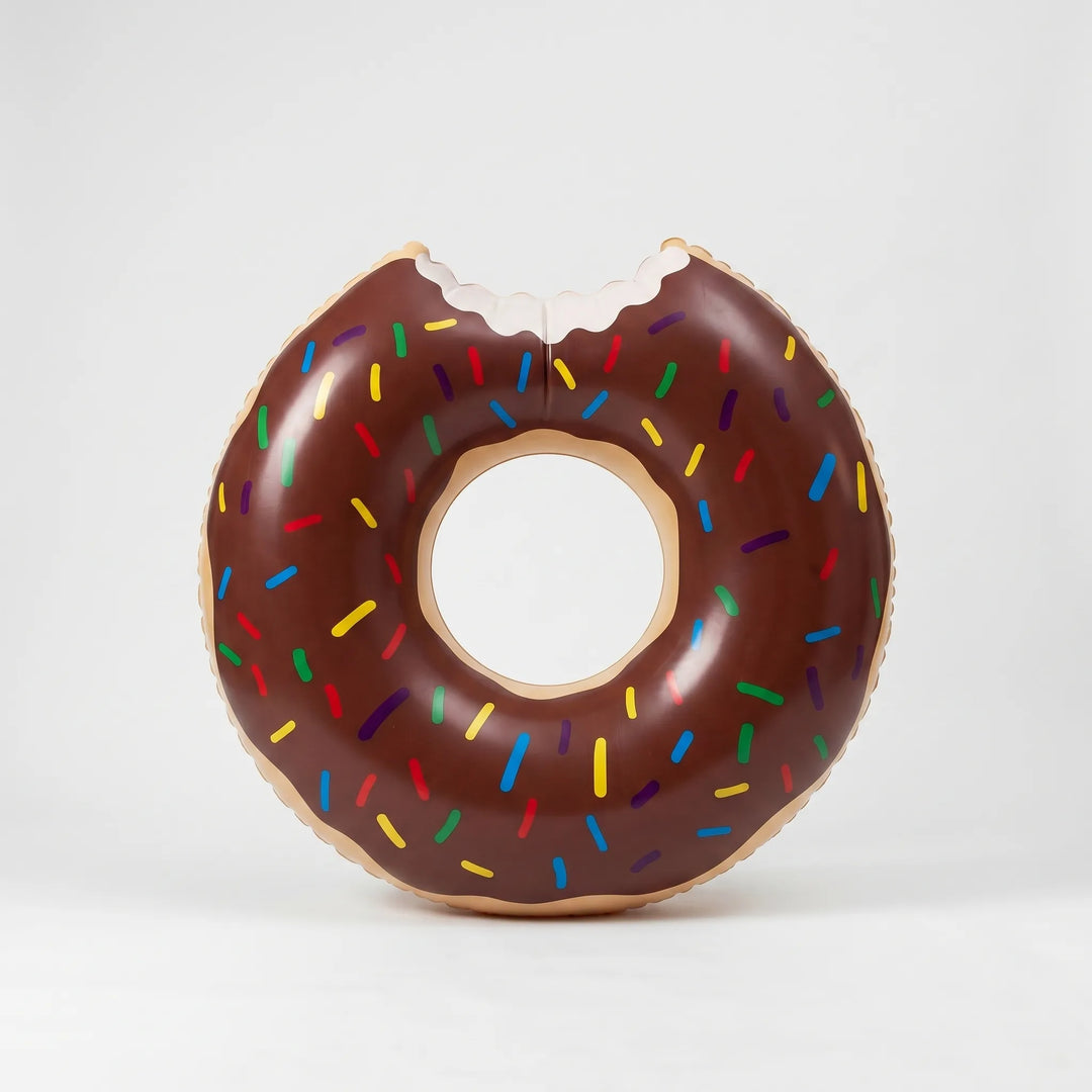 Happy child floating on a large inflatable donut water toy, enjoying a sunny summer pool day.