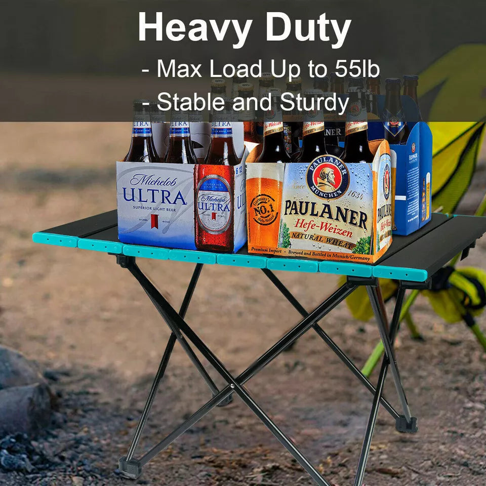 Compact lightweight aluminum folding camping table set up in a natural outdoor environment, ready for use.