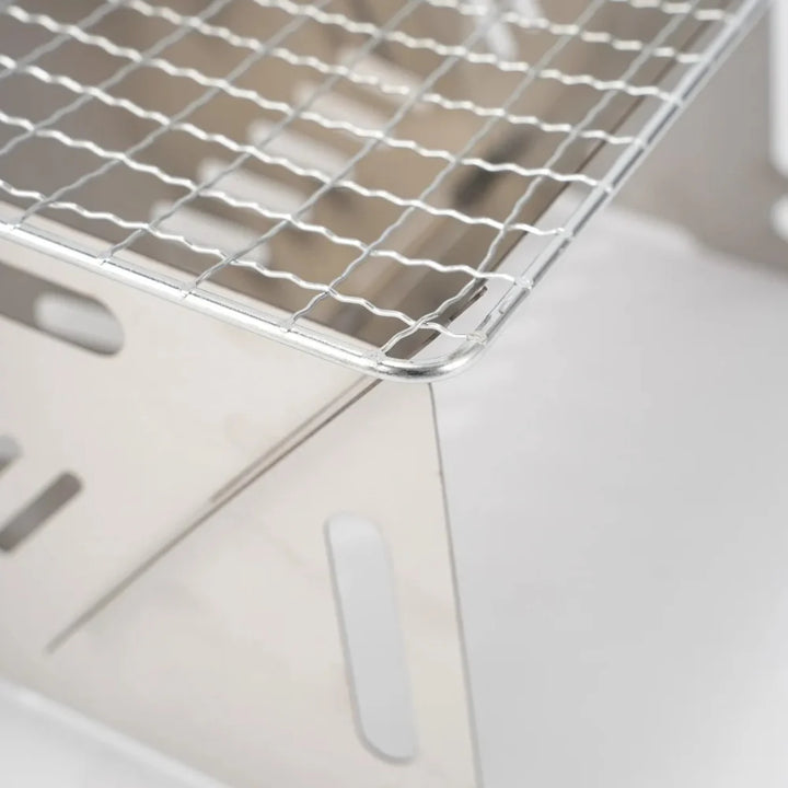 Folded stainless steel camping grill, perfect for portable outdoor cooking and survival gear.