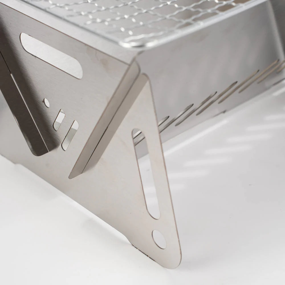 Unisex stainless steel camping grill set up, ready for outdoor cooking on a backpacking trip.