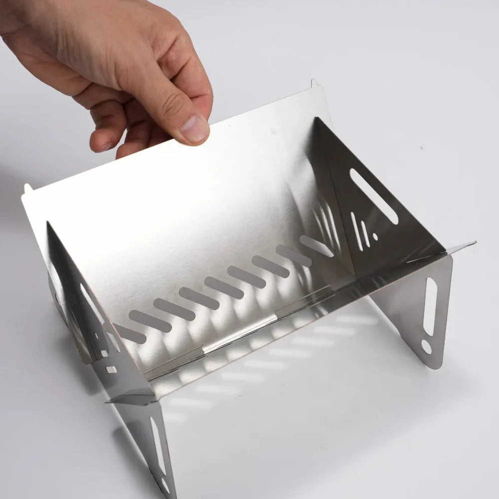 Unisex camping grill, stainless steel, folded next to a backpack, emphasizing portability.