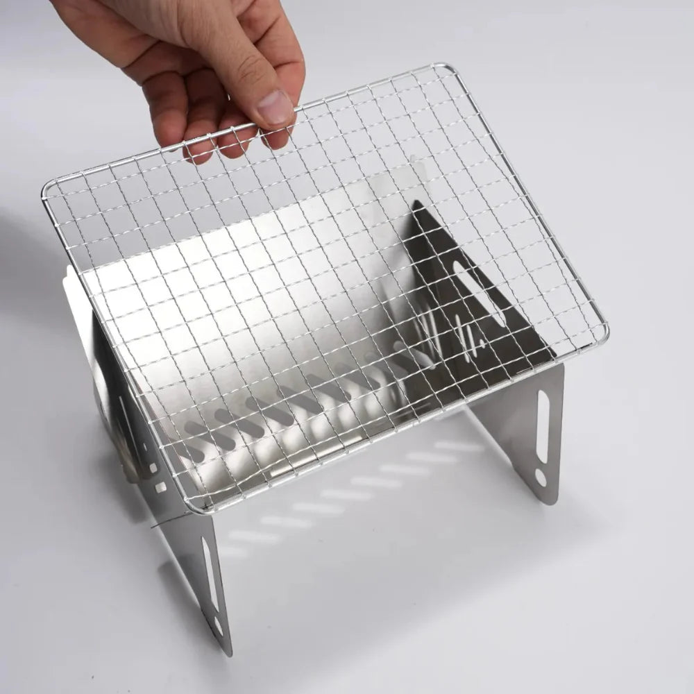 Portable stainless steel camping grill with a pot on top, demonstrating its use as a camp stove.