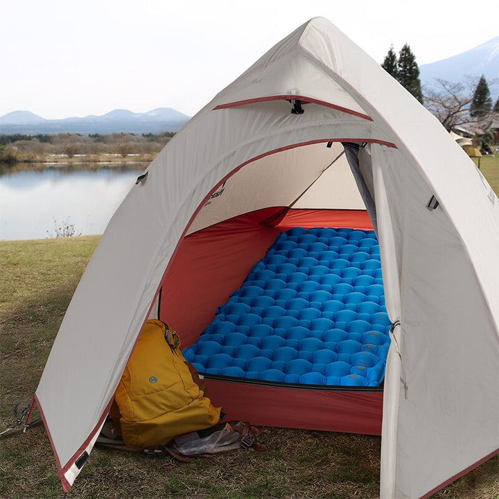 Person resting comfortably on an ultralight sleeping pad in a scenic outdoor setting, enjoying camping.