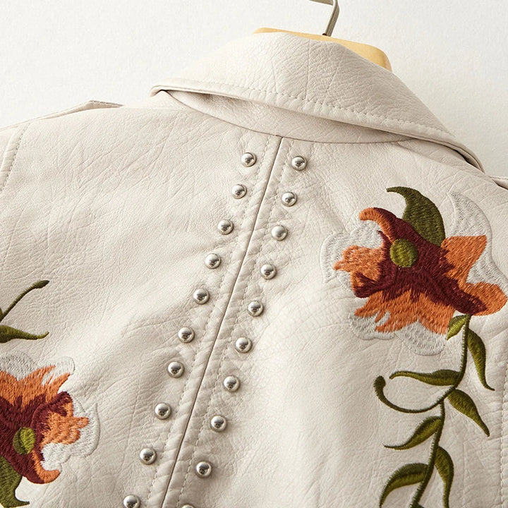Fashionable women's studded biker jacket with vibrant floral embroidery, adding a unique touch to any outfit.
