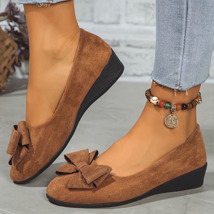 Black versatile women's wedge flats, round toe, slip-on, with a charming bow detail.