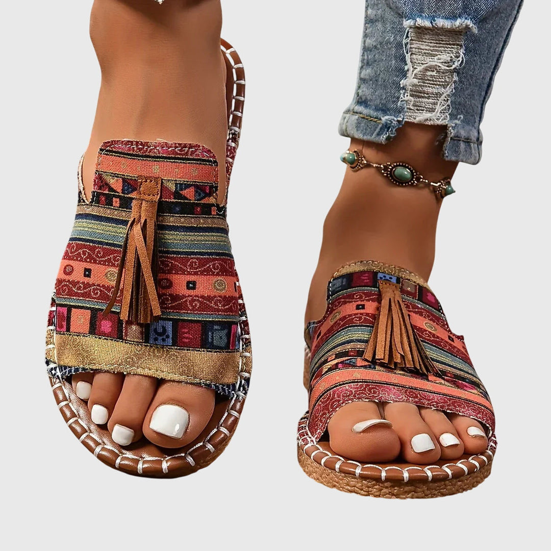 Women's comfortable slip-on sandals with tassel straps & flat sole for casual summer wear.