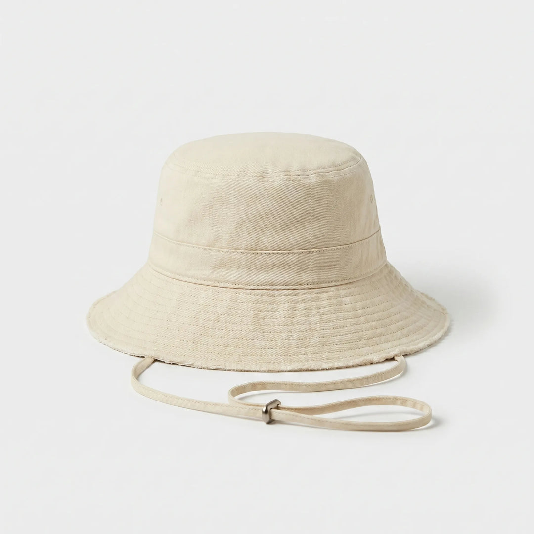 Casual women's summer bucket hat, distressed fabric, wide brim, and secure chin strap for sun protection.