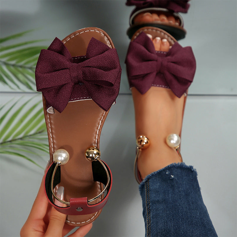 Comfortable flat sandals for women, adorned with a delicate bow and shimmering bead accents.