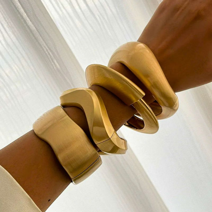 Four-piece set of women's gold tone wave cuff bracelets. Stylish stackable bangles, a vintage-inspired accessory.
