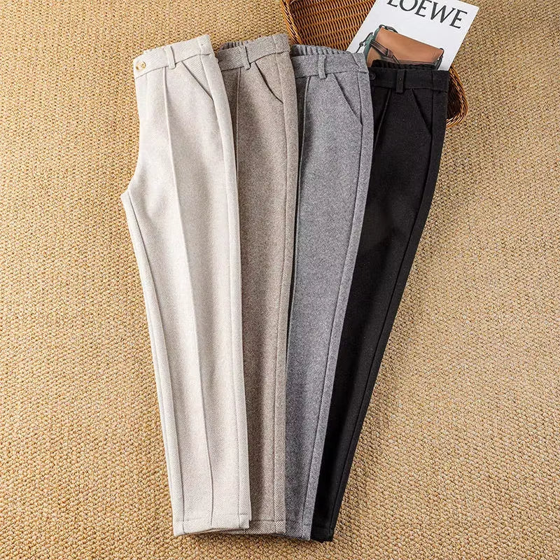 Full-length shot of a woman wearing high-waisted herringbone tailored trousers, elegant & sharp.