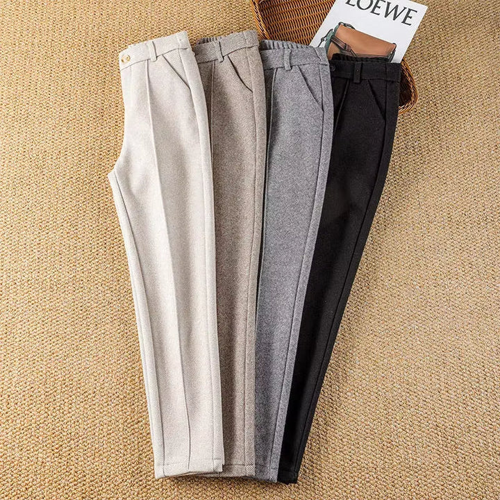 Full-length shot of a woman wearing high-waisted herringbone tailored trousers, elegant & sharp.