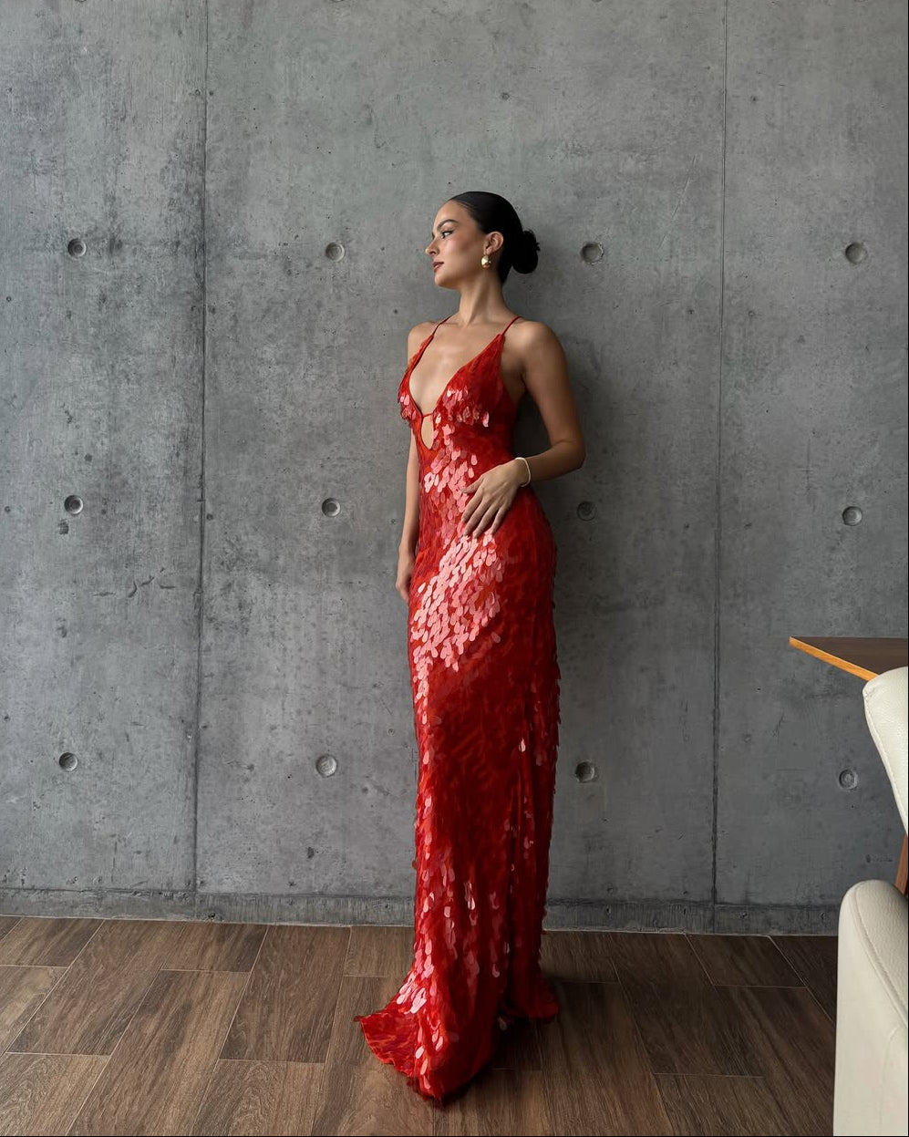 Flowing silhouette of a women's red sequin homecoming dress. Maxi length, plunge neck, ideal prom or cocktail wear.