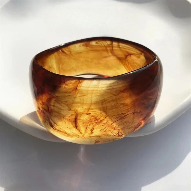 Close-up: Women's irregular acrylic bangle, showcasing unique marble pattern. Fashionable women's jewelry accessory.