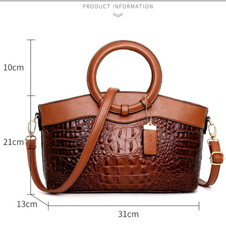 Detailed shot of the round handle on a women's vintage alligator-embossed handbag.